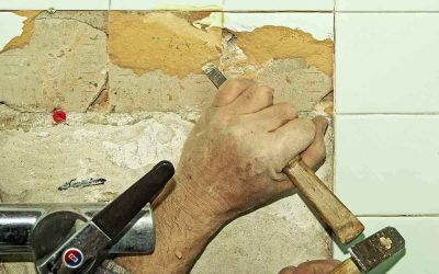 Une main utilise un marteau et un burin pour enlever une tuile