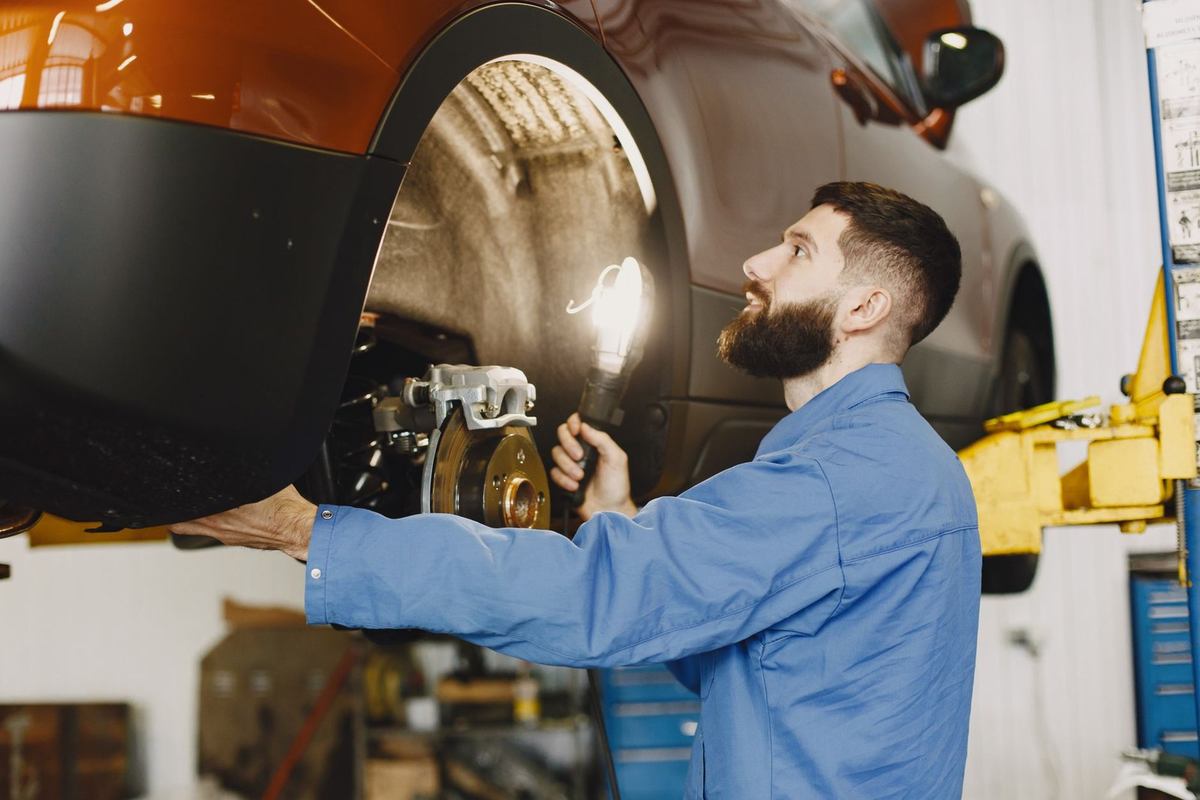 Mécanicien examine la roue arrière d'une voiture sur une nacelle Mécanicien examine la roue arrière d'une voiture sur une nacelle