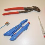 Outils de bricolage et fil bleu sur une surface blanche