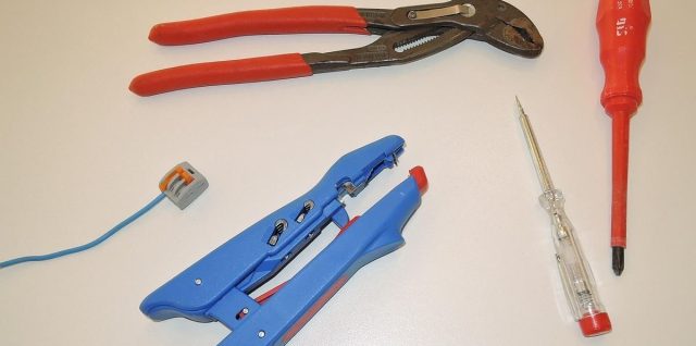 Outils de bricolage et fil bleu sur une surface blanche