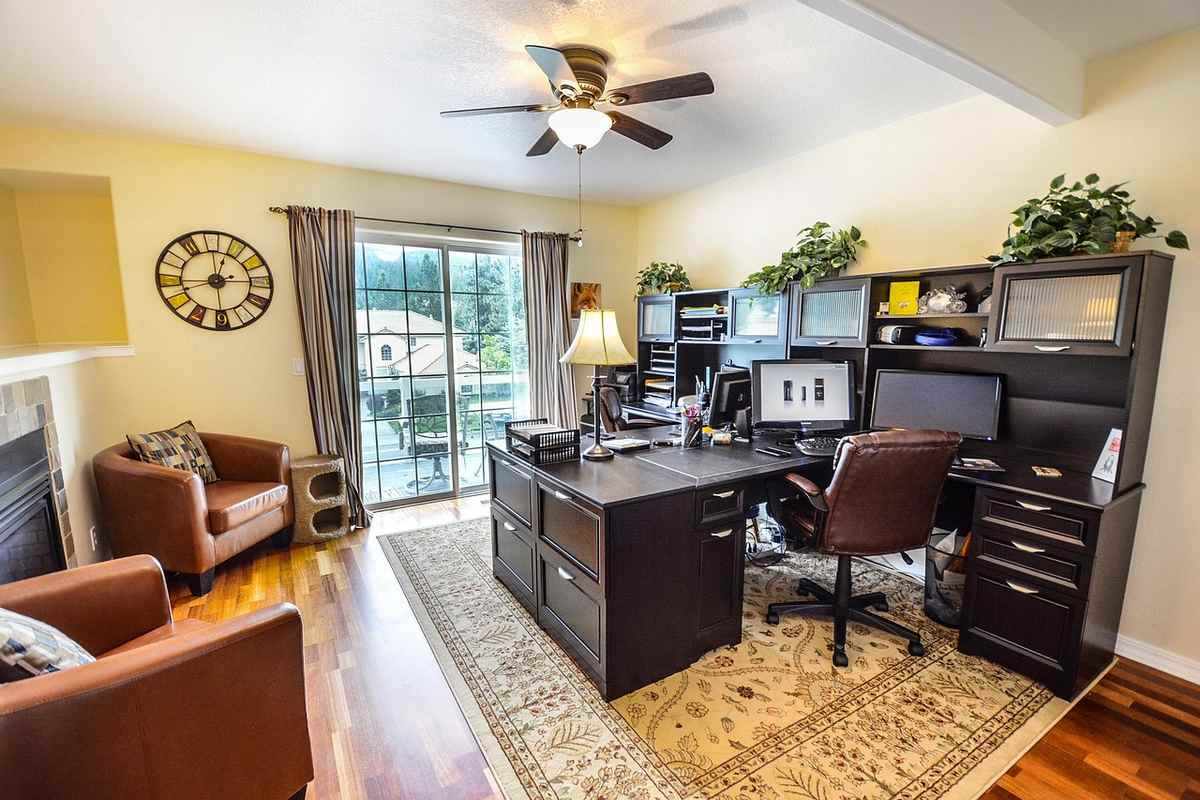 Un bureau moderne avec chaise ordinateur étagères tapis et vue sur terrasse Un bureau moderne avec chaise ordinateur étagères tapis et vue sur terrasse